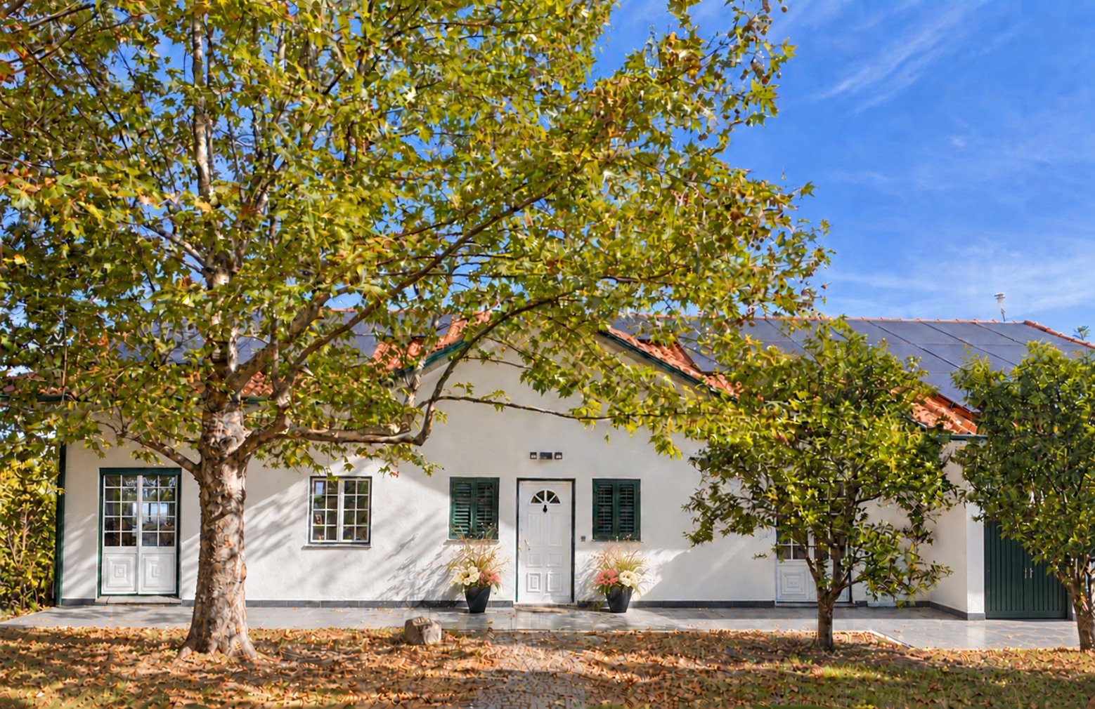 Garden-facing front of Quinta Arco-Íris, with mature trees and French doors